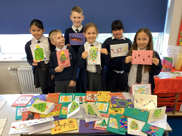 Children from St Oswalds CE Primary school with a table full of Christmas cards