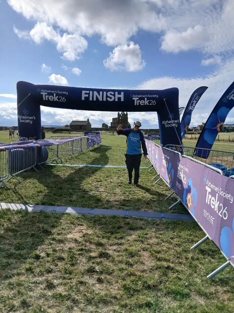 Paul Lawlor waving as he crosses the finish line of Trek26