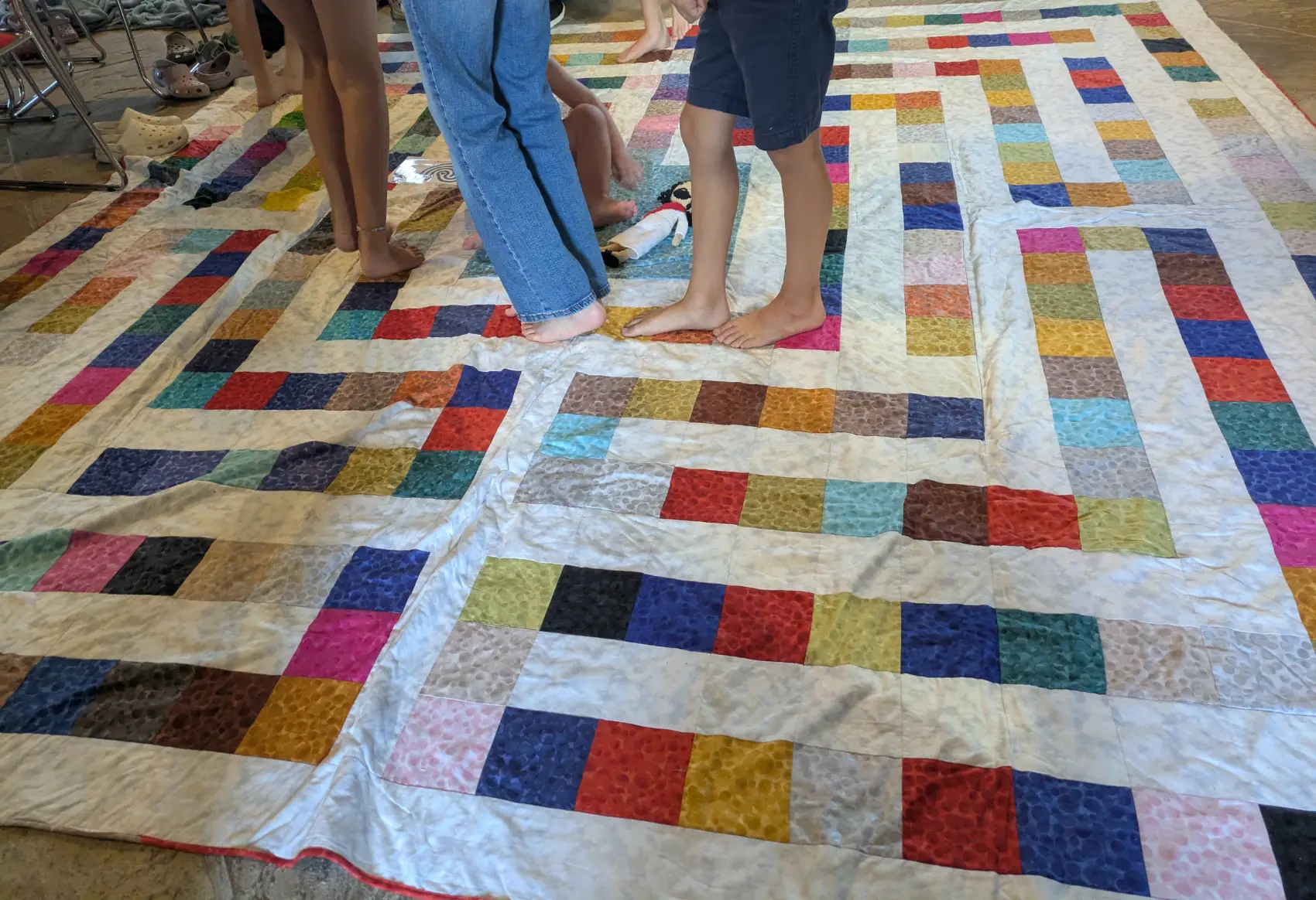 Children's legs walking around a labyrinth mat on the floor