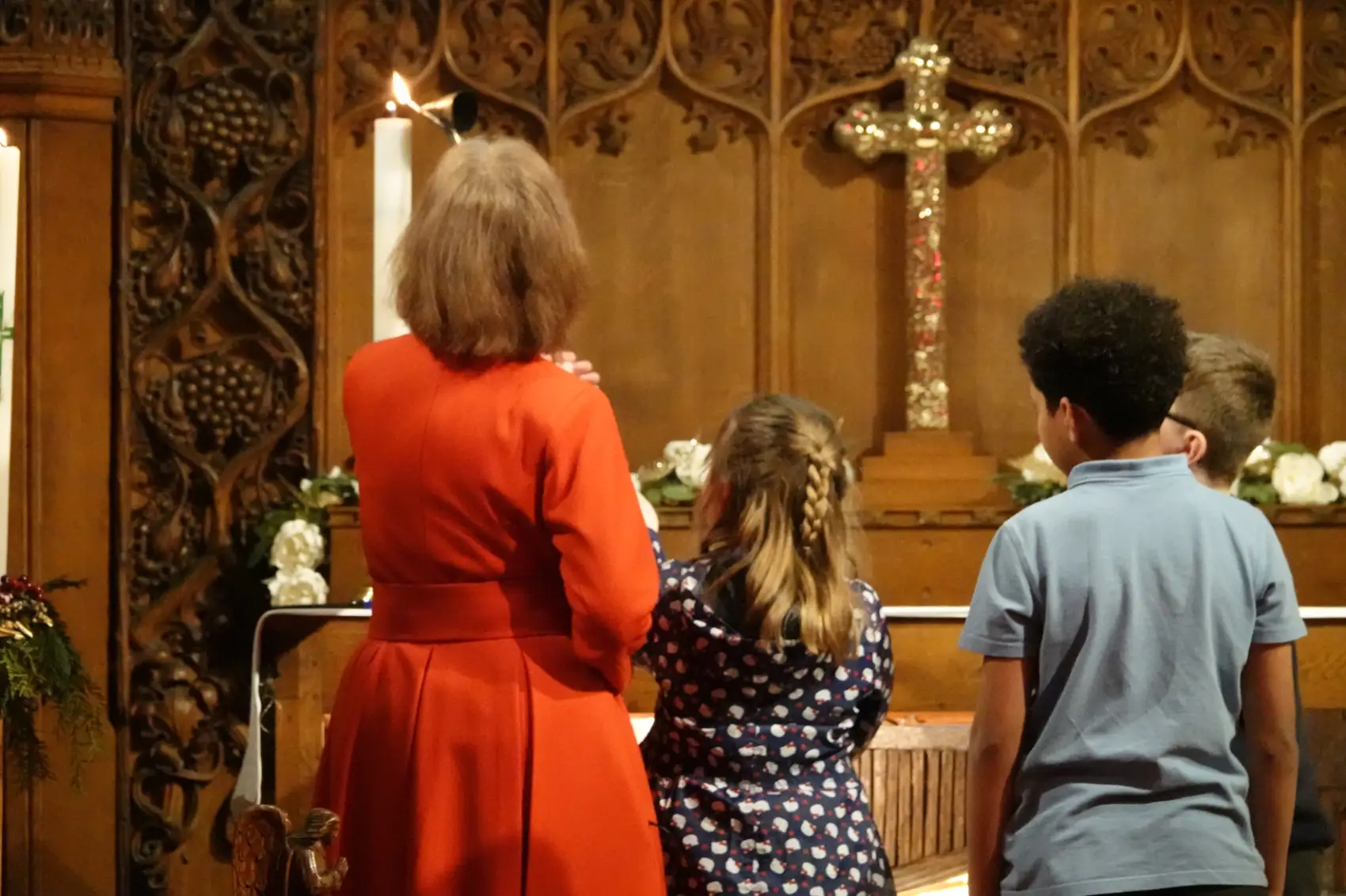 Revd Kalantha helps three children light a tall candle at the front of church