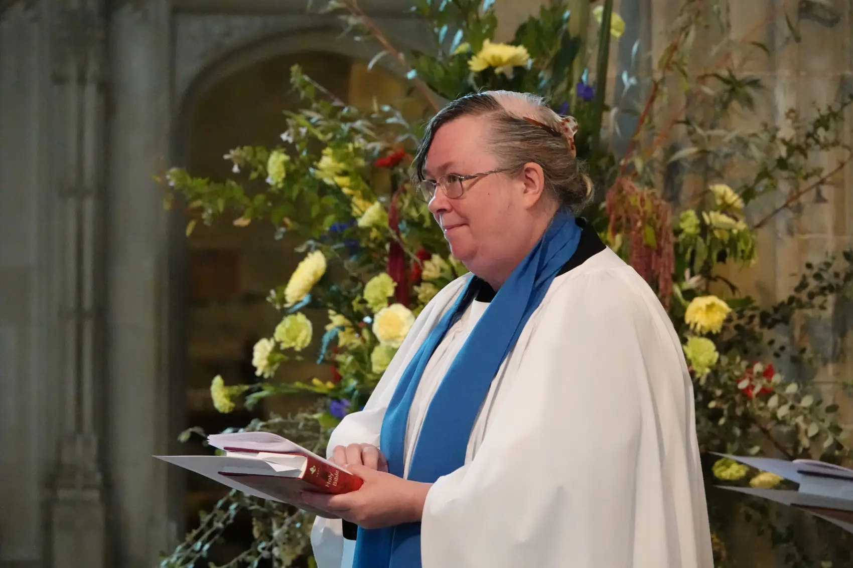 Andrea Stevens standing in the Cathedral holding some paperwork during the Reader service