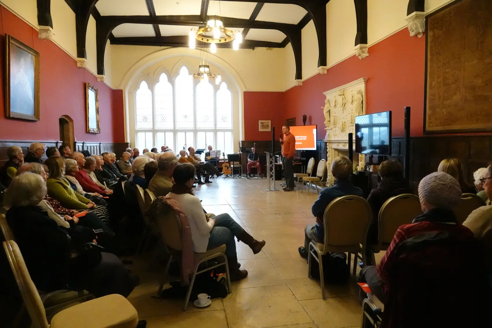 Patrick Watt speaking to a room full of people in the Great Hall at the Old Palace