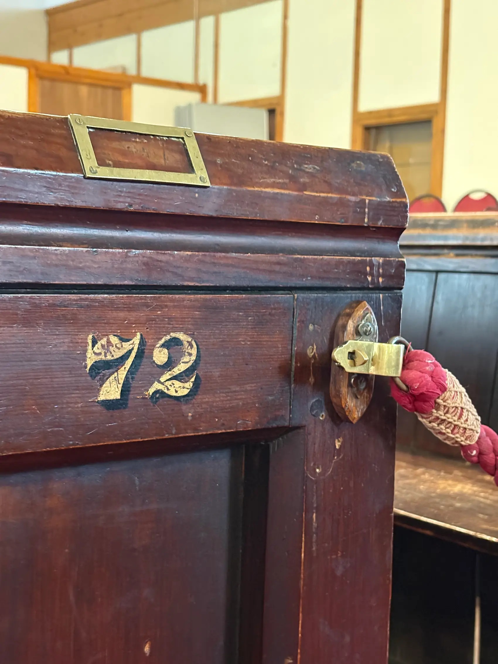 The end of a box pew with the number 72 painted on the side and a red rope stretching to the next pew