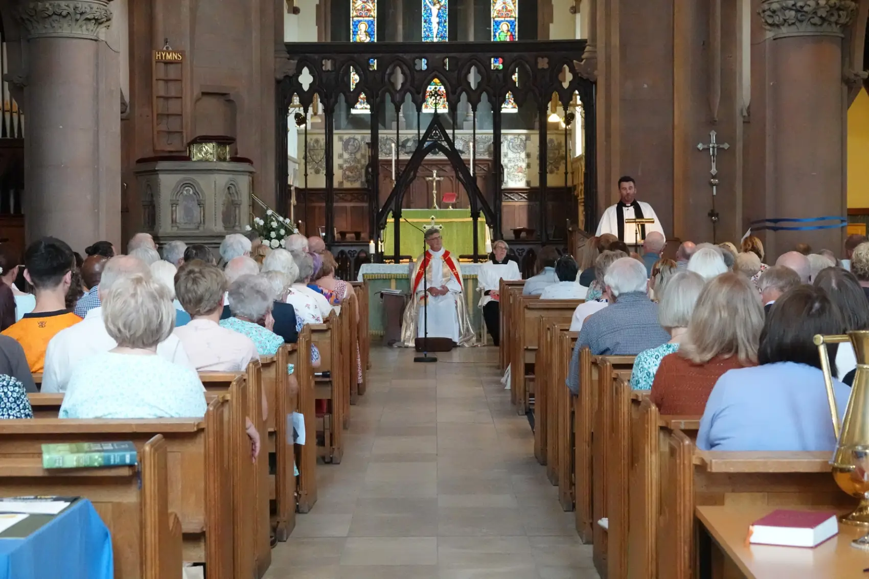 A picture from the back of church with Chris standing at the lecturn and Bishop Martin sitting at the front in the middle and the pews full of people