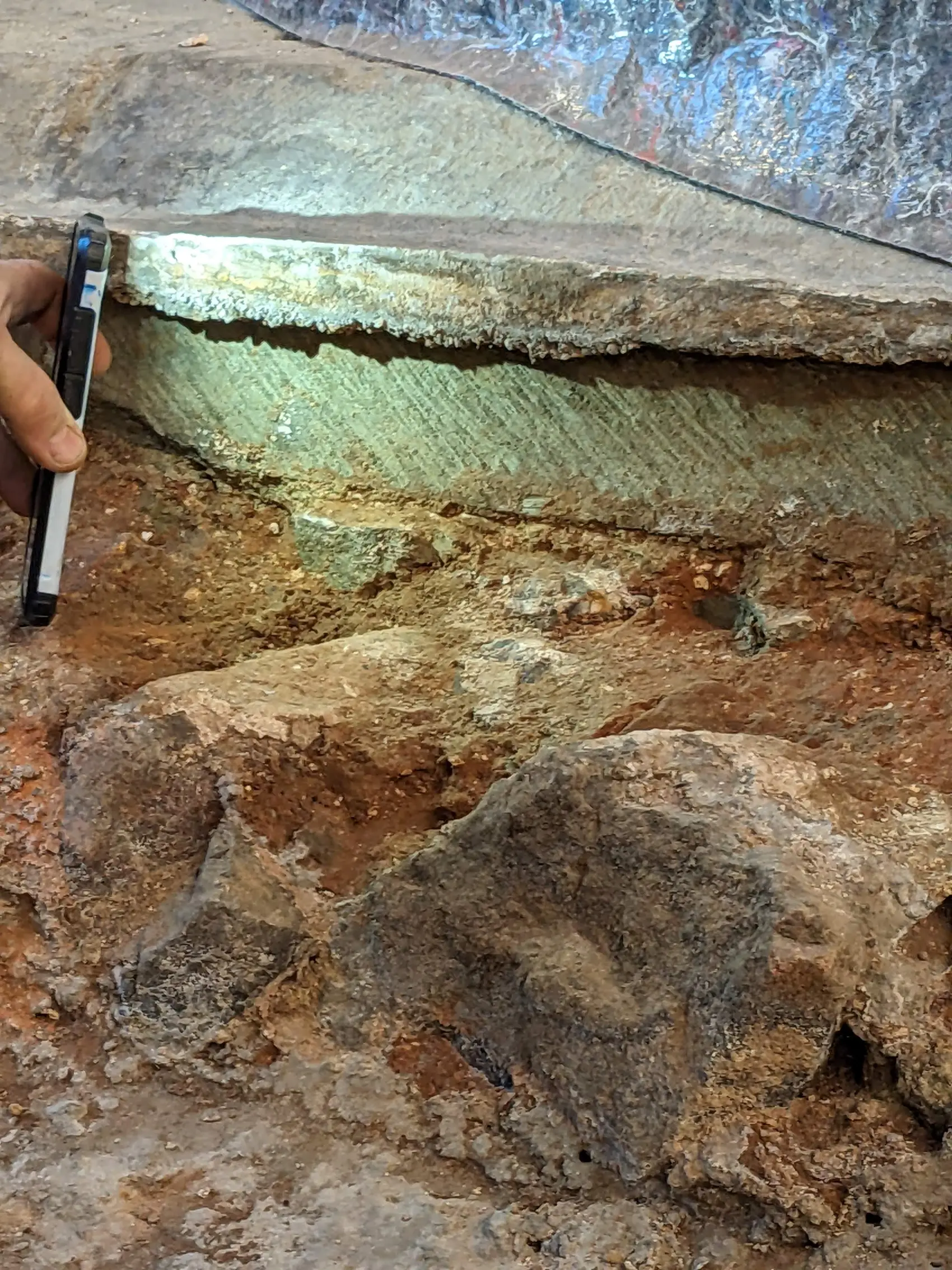 Light being shone onto the base of a pillar at the priory where you can see axe marks and a different colour patter.