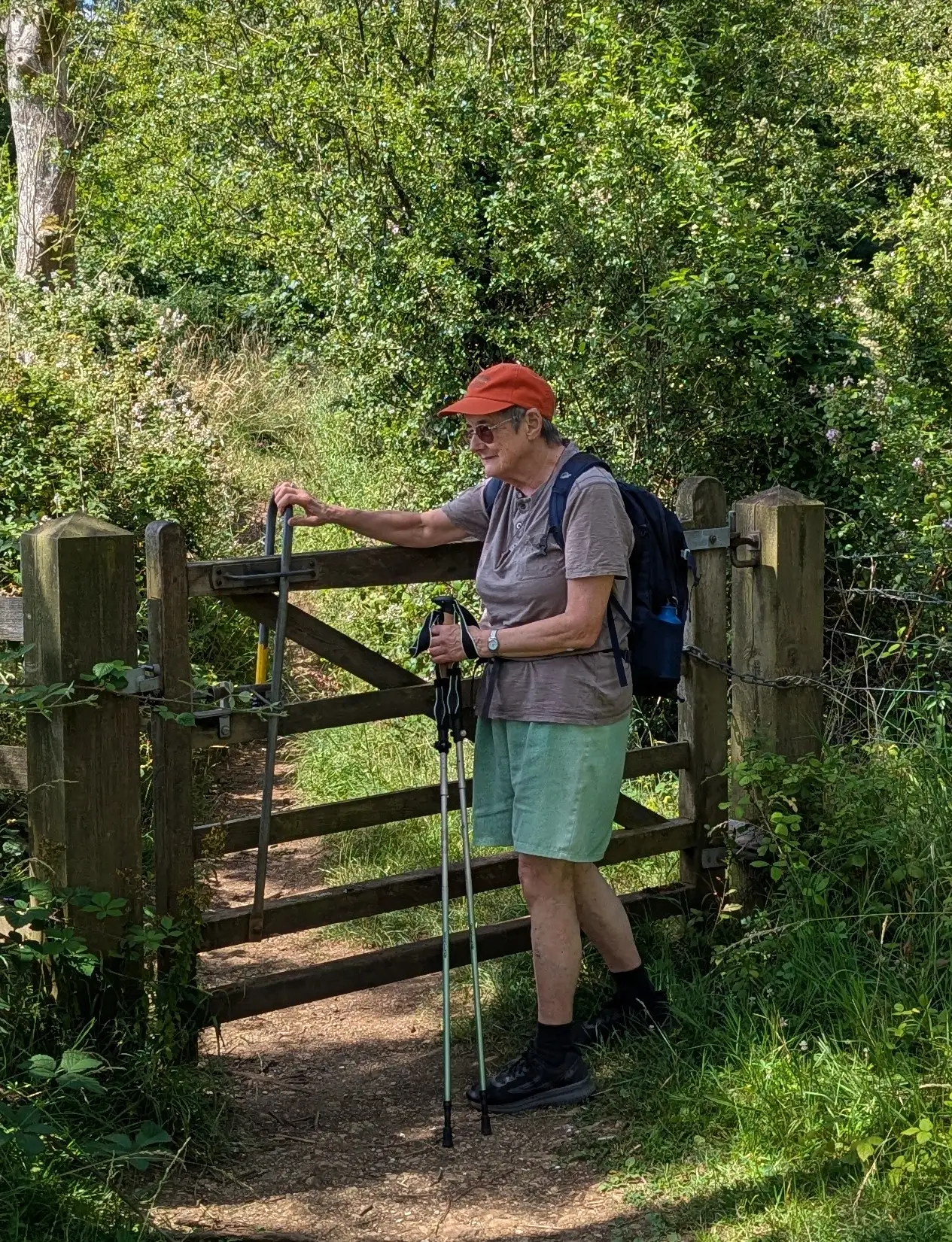 Lady in walking gear going through a gate next to a wood