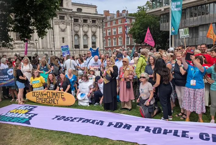 People at the climate protest in London standing behind a big banner