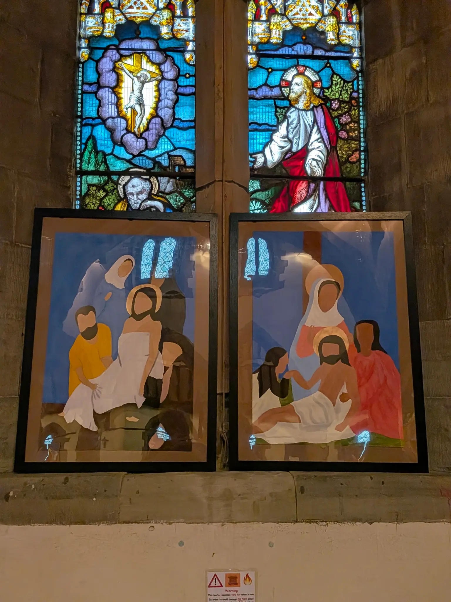 Two Stations of the Cross paintings in front of a stained glass window