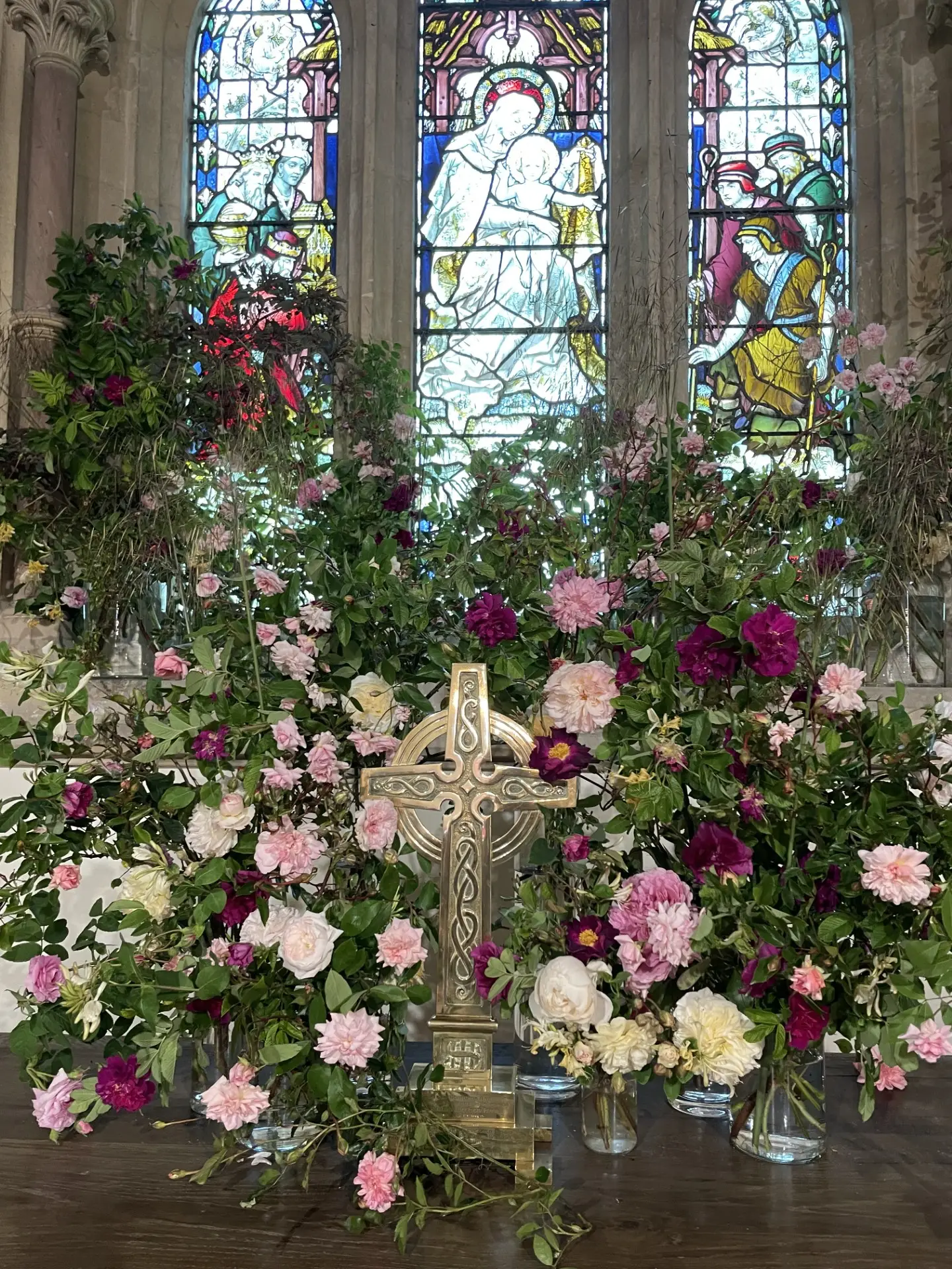 A display of flowers on an altar with a cross in the foreground