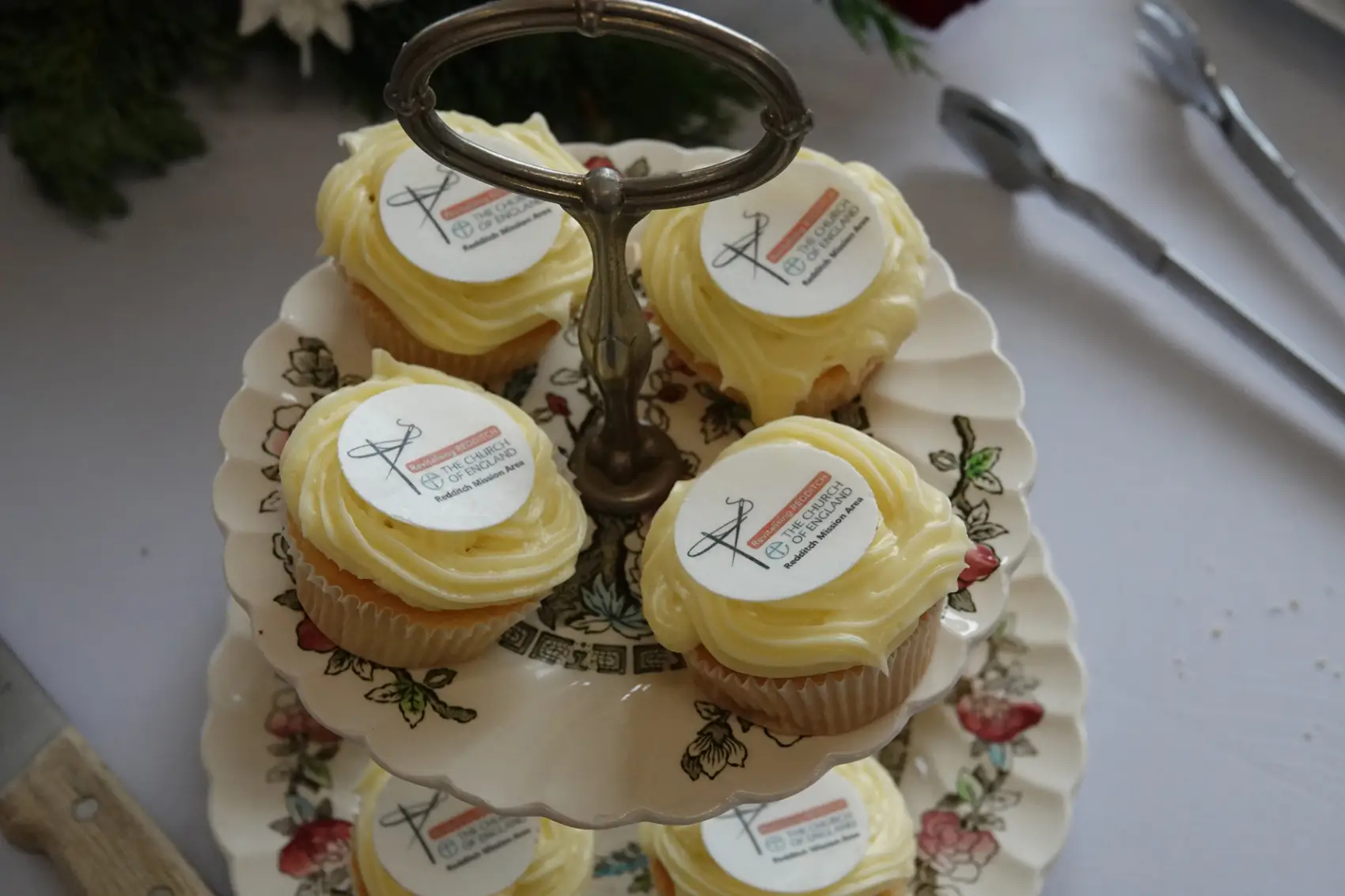 Fairy cakes on a 2 tiered cake stand which each have a 'Redditch Mission Area' edible topper