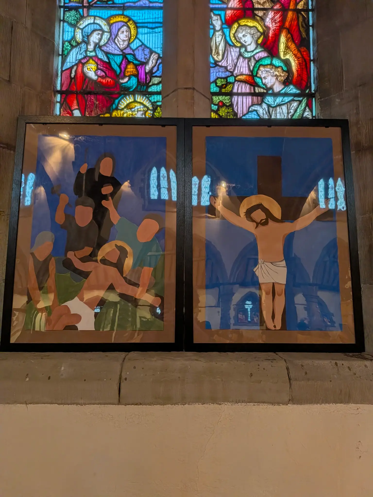 Two Stations of the Cross paintings in front of a stained glass window