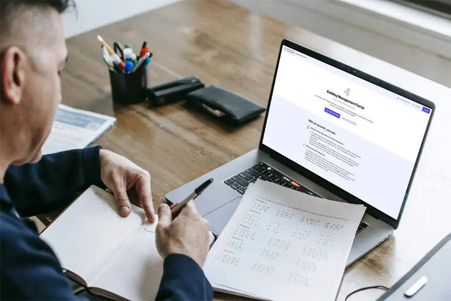 A man working at a desk with a laptop open in front of him with the church buildings management portal on the screen