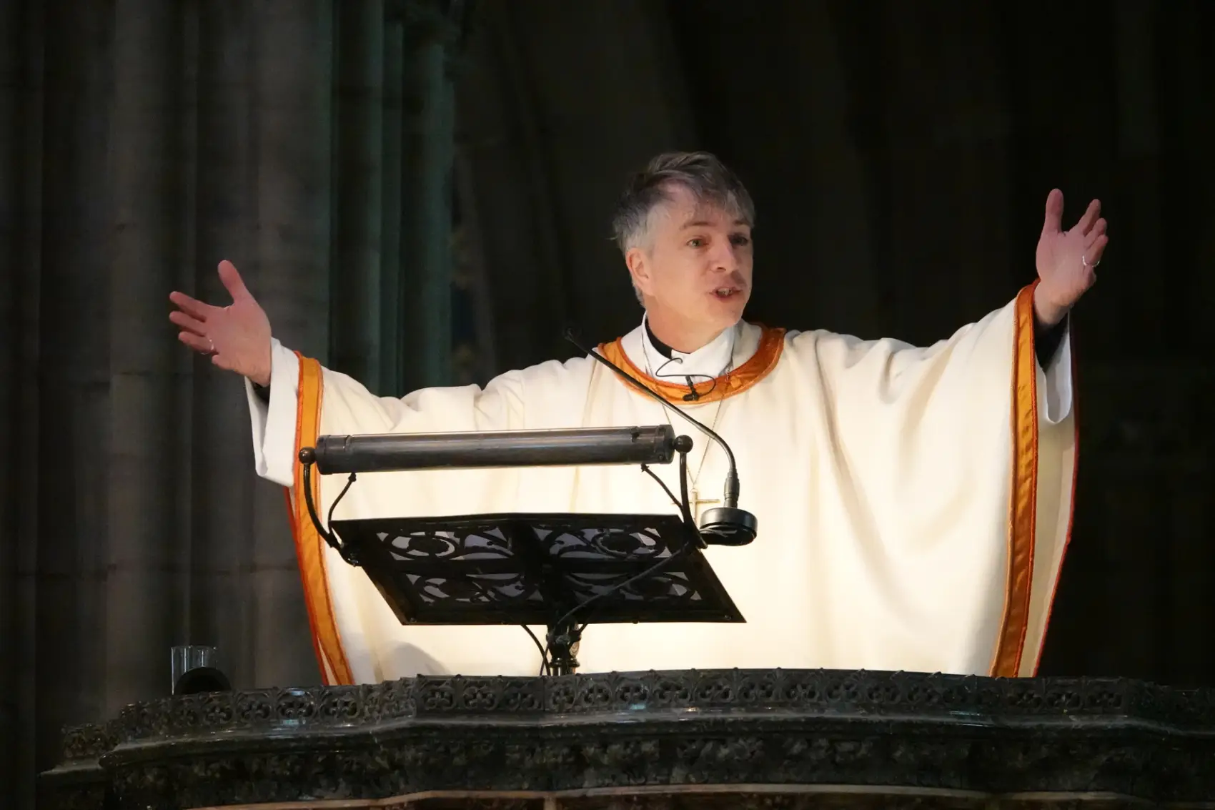 Bishop Hugh with his arms wide out as he preaches in the pulpit at the Cathedral
