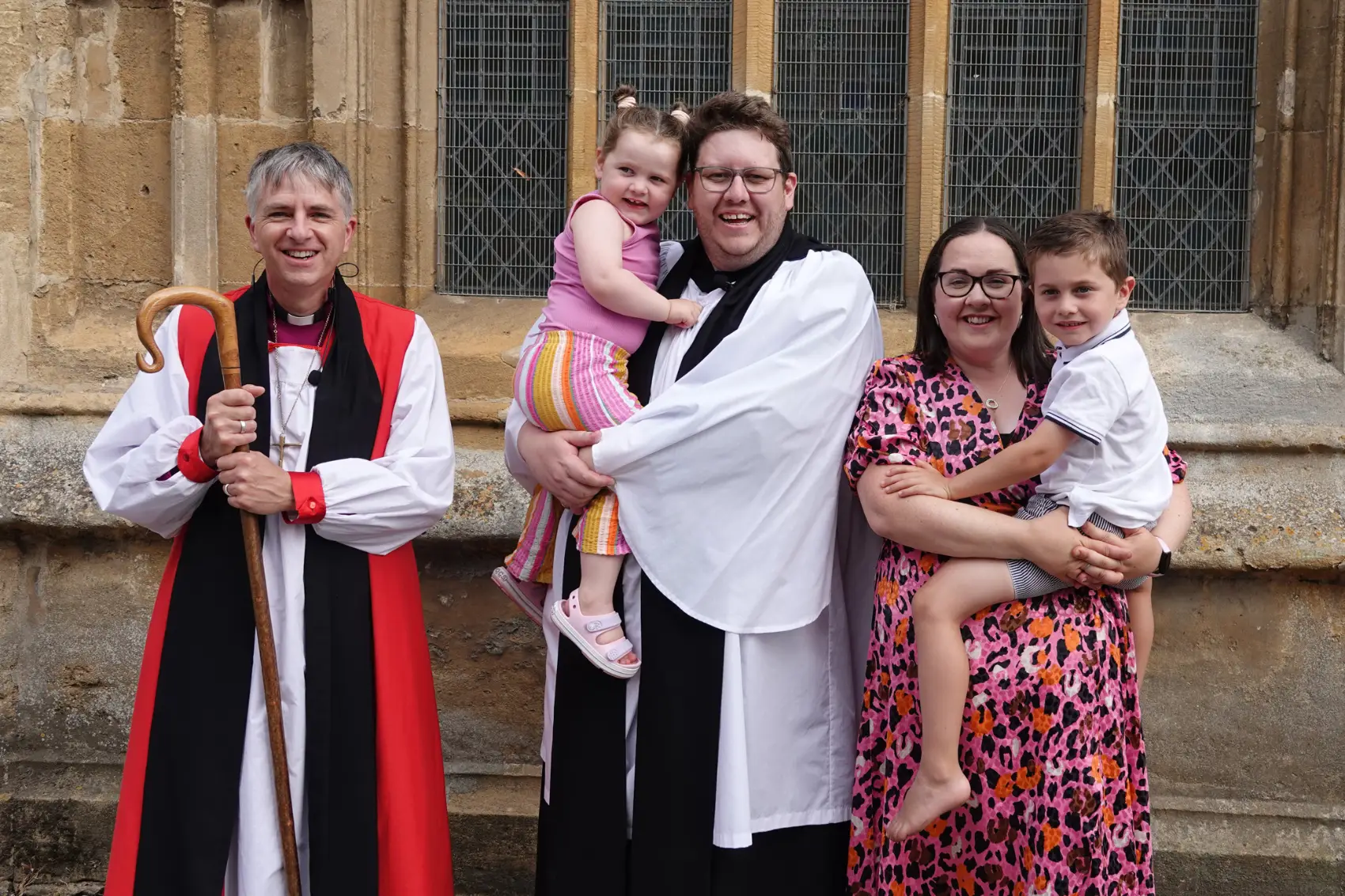 Mike Edwards and his wife standing outside Evesham church holding their children in the arms and standing next to Bishop Hugh