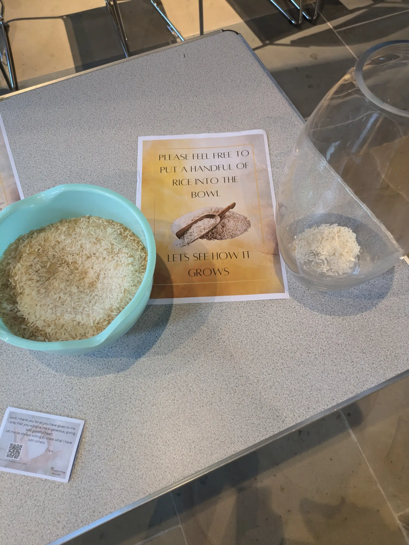 Bowl of rice with a sign to place a handful of rice into a nearby jar.