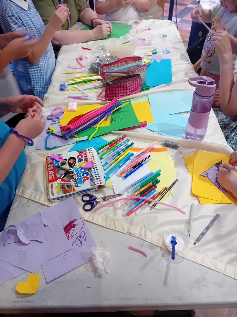 Hands of children as they are gathered around a table full of craft supplies