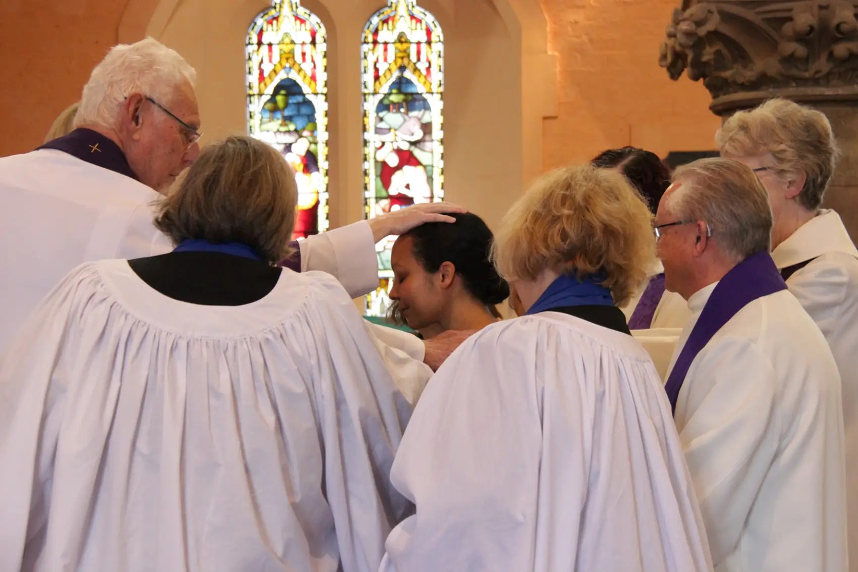 Heather Murphy in a huddle of ministers with a hand on her head as they pray for her