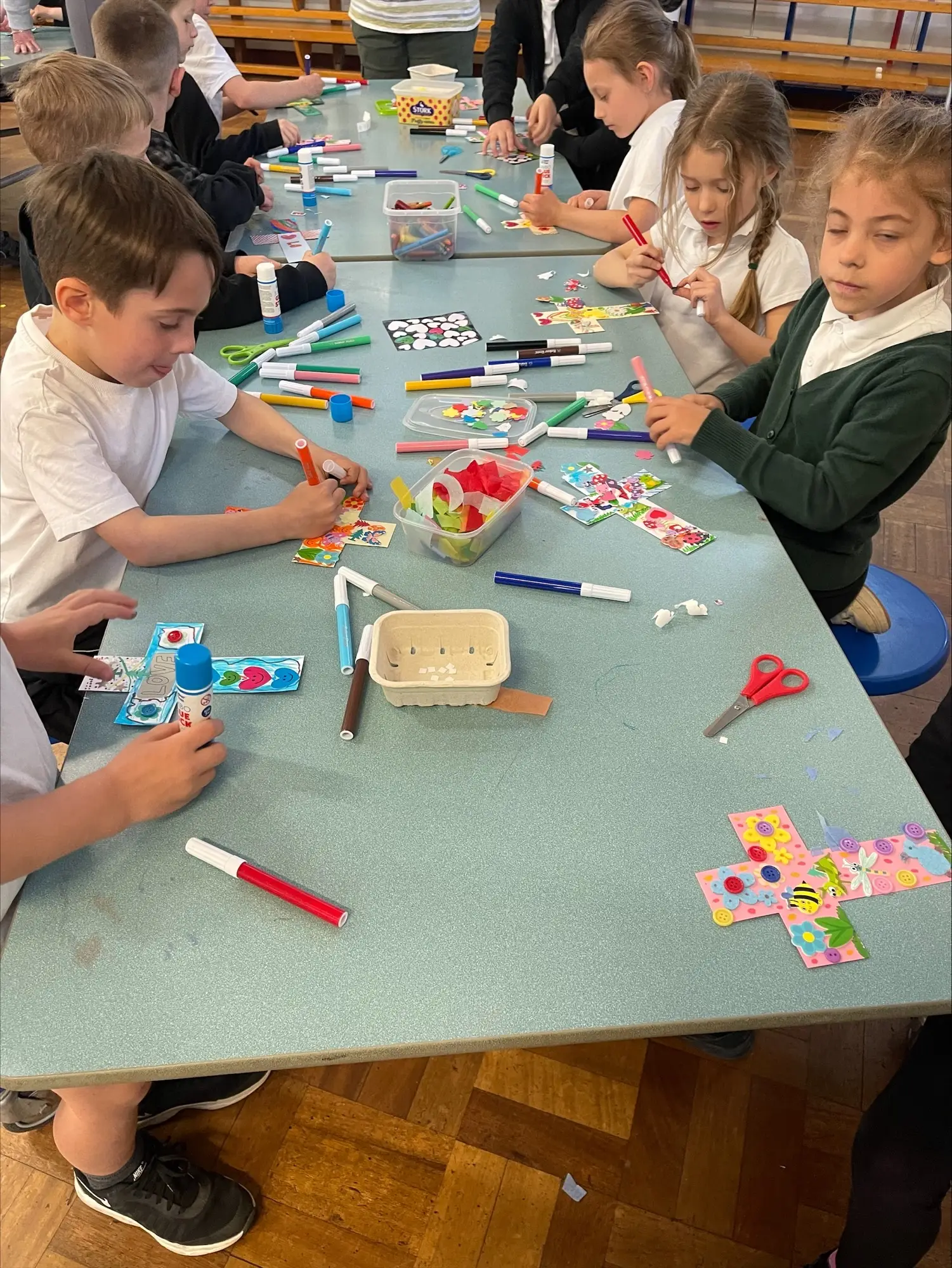 Children sitting around a table colouring in crosses