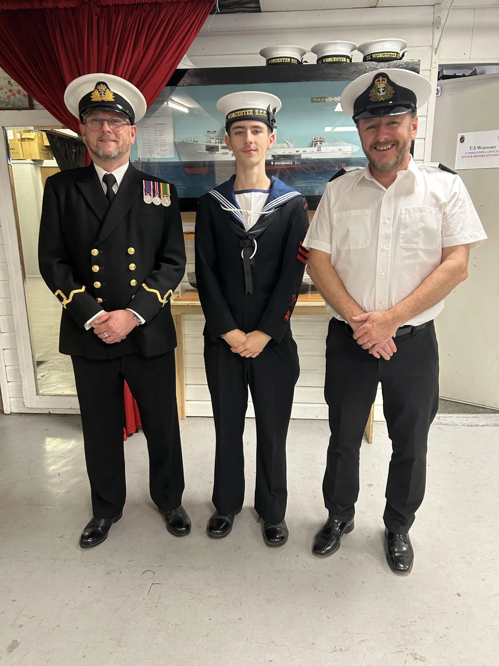 Photo showing three people in uniform standing together. 