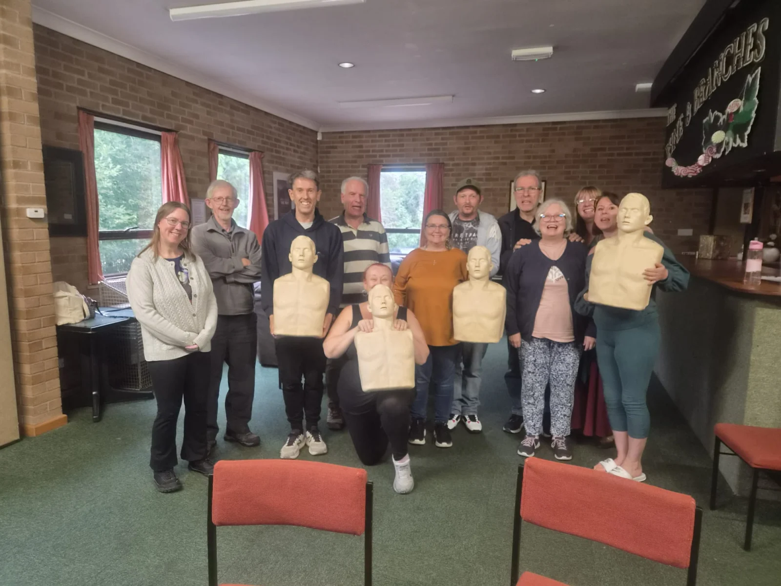 A group of people holding resuscitation dummies standing in Lye church hall 