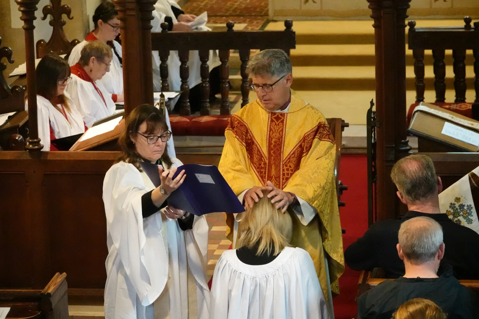 Bishop Martin with his hands on Penny Gordon's head as he ordains her Deacon. She is kneeling before him at the front of Wick Church